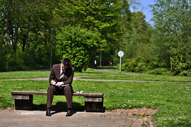 公園のベンチで座って勉強する男性